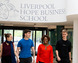 Four students walking through the main corridor of the Business School